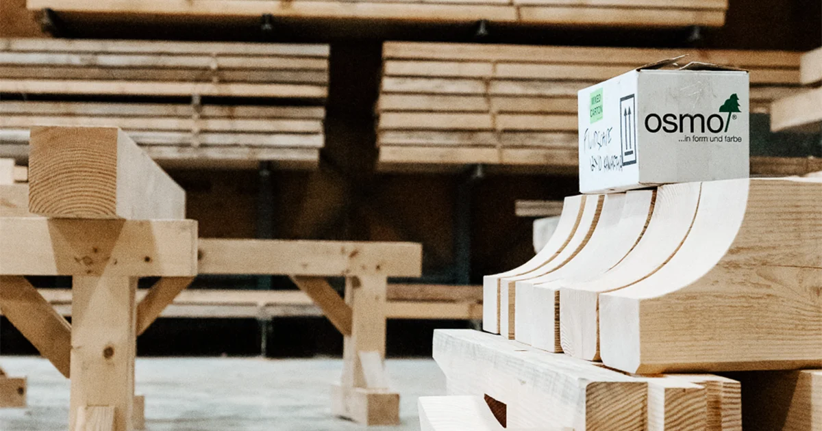  A woodworking shop with stacked wooden beams and precision-cut timber pieces labeled with Osmo wood treatment.